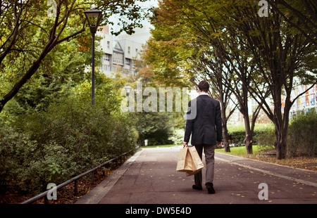 Einsamkeit, einsamer Mann mit Einkaufstüten Spaziergang nach der Arbeit Stockfoto