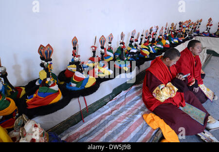 Lhasa, Tibet. 28. Februar 2014. Zwei tibetische buddhistische Mönche machen Sie eine Pause während ein Cham-Tanz-Ritual gehalten, um die bevorstehende Losar im Kloster Tsurphu in Doilungdeqen County von Lhasa, Hauptstadt von Südwesten Chinas Tibet autonome Region, 28. Februar 2014 feiern. Der Cham-Tanz ist ein Ritual durchgeführt von tibetisch-buddhistischen Mönchen um böse Geister auszutreiben. Die Tänzer tragen Masken verschiedener Tiere und Fabelwesen, wie sie zur Begleitung der religiösen Musik durchzuführen. Bildnachweis: Xinhua/Alamy Live-Nachrichten Stockfoto