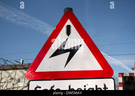 Hochspannung overhead Elektrokabel Warnschild am Bahnübergang Stockfoto