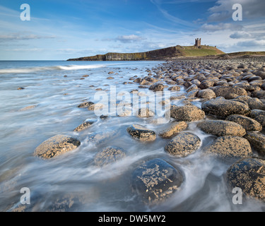 Die Ruinen von Dunstanburgh Castle mit Blick auf den Felsen verstreut Küste von Embleton Bay, Northumberland, England. Stockfoto