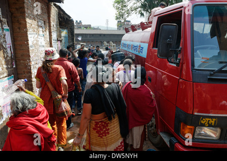 Nepalesische Frauen (und neugierige Touristen) Masse ein frisches Wasser Lieferung runde Lkw in Kathmandu, Nepal Stockfoto