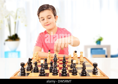 Kleiner Junge spielt Schach sitzen auf einem Tisch zu Hause Stockfoto