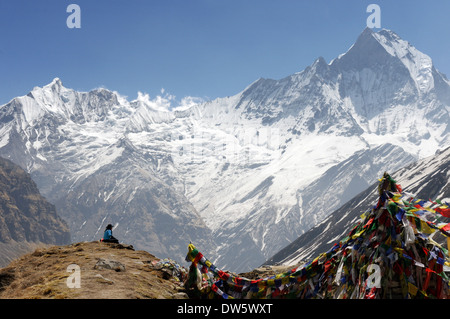 Eine Dame Trekker sitzt bewundern die riesige Landschaft im Annapurna Sanctuary, Nepal Stockfoto