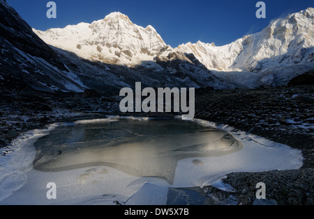 Einem zugefrorenen See in der Dämmerung im Annapurna Sanctuary, Nepal. Die Wand auf der rechten Seite des Bildes ist die Südwand des annapurna Stockfoto