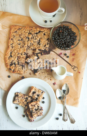 Blick hinunter auf das Frühstück mit hausgemachten Heidelbeerkuchen, Schüssel mit frischen Heidelbeeren und weißen Tasse Tee Stockfoto