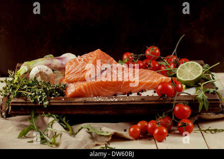 Frischer Lachs Salzfisch auf Vintage-Board mit Gemüse und Gewürzen Stockfoto