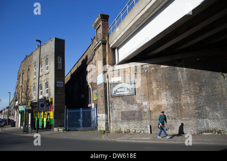 Straßenszene in Brixton als Mann geht unter einer Eisenbahnbrücke. London, UK. Stockfoto