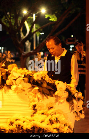 Taipei, Taiwan-Februar 28, 2014:228 Friedenspark in der Nacht. Ein Mann liest Inschriften auf der Pest während Polizei überwacht hinter während der Jahrestag des 1947 Massakers denen Tausende von nationalistischen Kuomintang-Truppen aus China, an der Taipei Peace Park am 28. Februar 2014 getötet wurden. Das Massaker blieb für Jahrzehnte unter der späten nationalistischen KMT Führer Chiang Kai-shek der Regel Tabu. Es war nicht bis 1995, dass die damaligen Präsidenten Lee Teng-Hui die erste offizielle Entschuldigung gemacht. Parlament später vereinbart, die Opfer zu entschädigen und 28 Februar ein offizieller Feiertag. Stockfoto