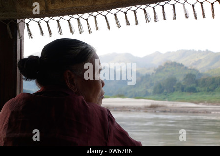 Laotische Frau Blick aus einem langsamen Boot hinunter den Mekong in Laos. Stockfoto