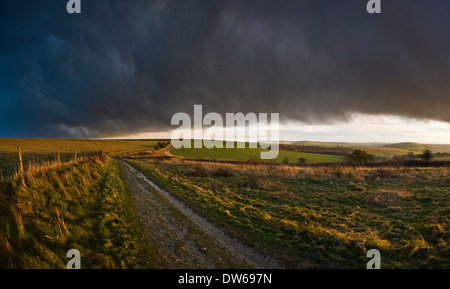 Die späten Sonne bricht durch dunkle Regenwolken über den South Downs auf Kithurst Hügel in der Nähe von Storrington, West Sussex Rollen Stockfoto