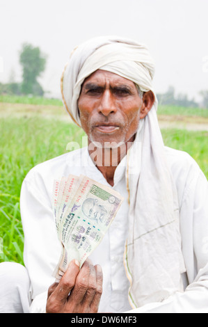 1 indische Bauern sitzen und zeigen Rupien Stockfoto