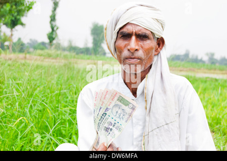 1 indische Bauern sitzen und zeigen Rupien Stockfoto