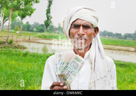 1 indische Bauern stehen und zeigt Rupien Stockfoto