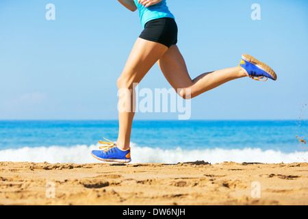 Sportliche blonde Frau in Sportbekleidung Joggen an einem sonnigen Strand Stockfoto