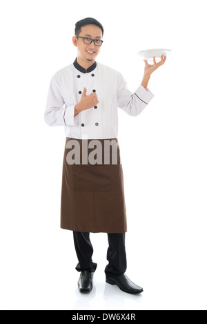 Ganzkörper asiatischen Koch hält einen leeren Teller bereit für Lebensmittel, Daumen und isoliert auf weißem Hintergrund stehen. Stockfoto
