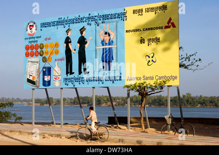 Ein kleiner Junge reitet ein Fahrrad vorbei ein großes Plakat Warnung vor den schädlichen Auswirkungen der Verwendung von Drogen in Stung Treng, Kambodscha. Stockfoto