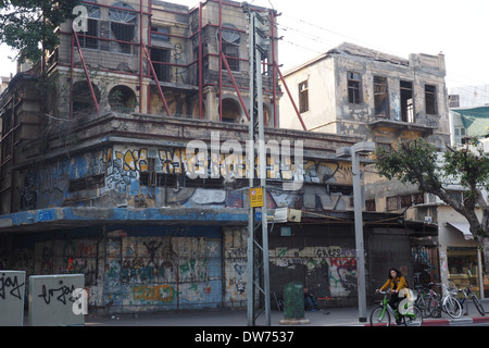 Radsportler entlang Allenby Street vor dem verlassenen Gebäude voller Graffiti in Tel Aviv Stockfoto