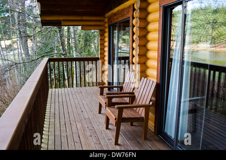 Log cabin Deck mit zwei Stühle aus Holz mit Blick auf den See durch den Wald. Bei Cusheon Lake Resort auf Salt Spring Island, British Columbia, Kanada. Stockfoto