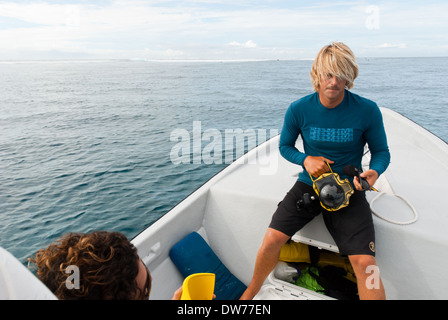 Ein Surf-Fotograf bereitet seine Ausrüstung vor dem Tauchen aus dem Boot, Surfer in Cloudbreak Tavarua Insel zu erfassen. Stockfoto