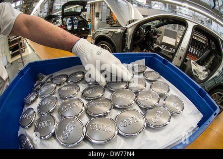 Ein Mitarbeiter hält Audi Emblem vor ein Audi A3 im Audi-Werk in Ingolstadt, Deutschland, 28. Februar 2014. Foto: Armin Weigel/dpa Stockfoto