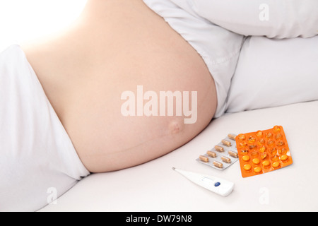 Schwangere Frauen mit Medikamenten im Bett Stockfoto