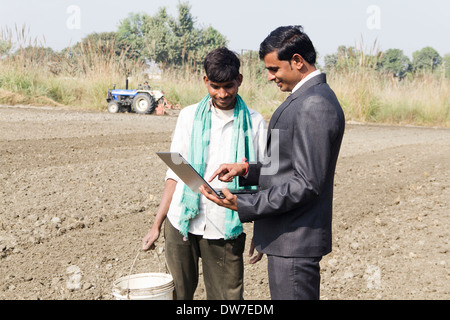 Landwirt in Plowedfield und Busineeman stehen mit laptop Stockfoto