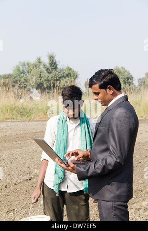 Landwirt in Plowedfield und Busineeman stehen mit laptop Stockfoto