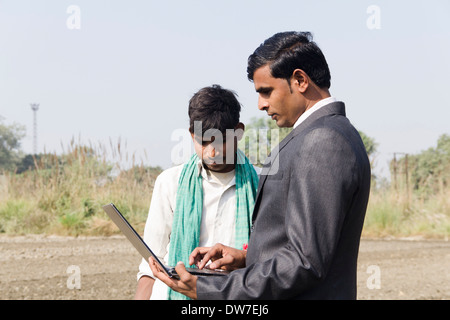 Landwirt in Plowedfield und Busineeman stehen mit laptop Stockfoto