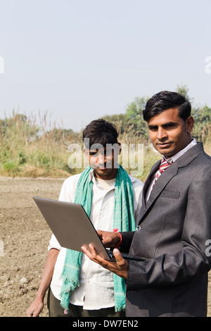 Landwirt in Plowedfield und Busineeman stehen mit laptop Stockfoto