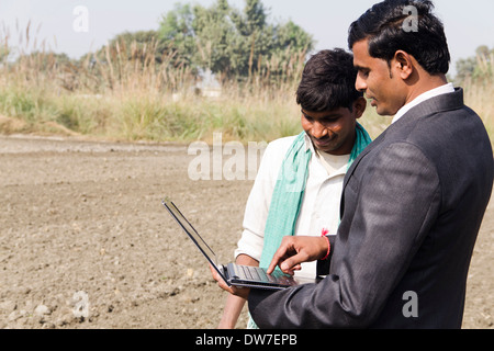 Landwirt in Plowedfield und Busineeman stehen mit laptop Stockfoto