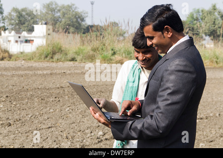 Landwirt in Plowedfield und Busineeman stehen mit laptop Stockfoto