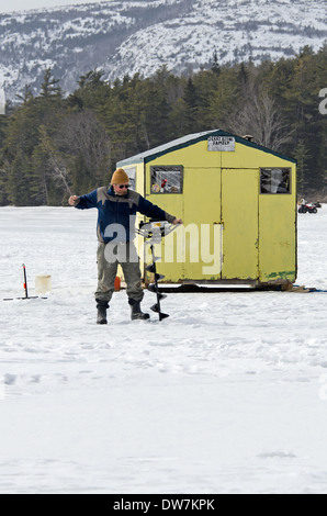 Mann, die Bohrung im Eis außerhalb Eis Angeln Shack auf dem Eagle Lake, Acadia National Park, Maine Stockfoto