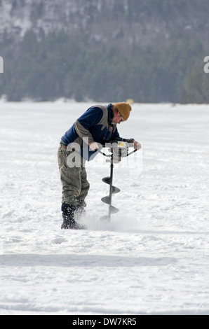 Bohrung für Eisangeln auf dem Eagle Lake, Acadia National Park, Maine Mann Stockfoto