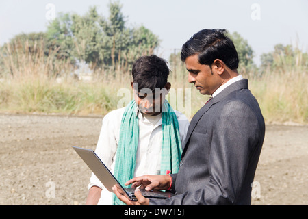 Landwirt in Plowedfield und Busineeman stehen mit laptop Stockfoto