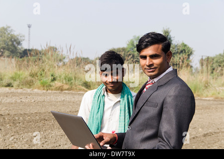 Landwirt in Plowedfield und Busineeman stehen mit laptop Stockfoto