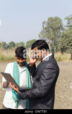 Landwirt in Plowedfield und Busineeman im Gespräch mit Mobil arbeiten Stockfoto