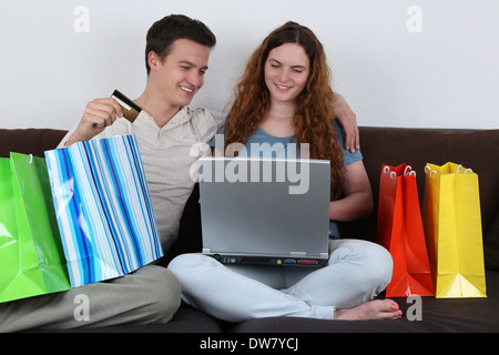 Ein junges Paar mit Einkaufstüten nutzt einen Laptop-Computer für Internet-shopping Stockfoto