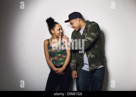 Schöne junge Paar auf grauem Hintergrund. Fröhlicher junger Mann und junge Frau, die gemeinsam Spaß haben. Stockfoto