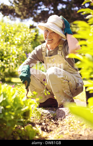 Glückliche ältere Frau im Garten im Hinterhof Blick auf die Kamera zu Lächeln Stockfoto