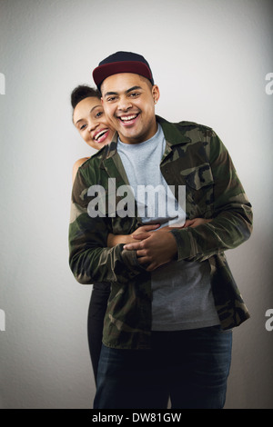 Fröhliche hispanische junges Paar gemeinsam auf grauem Hintergrund. Junge Frau mit ihrem hübschen Freund in die Kamera Lächeln. Stockfoto