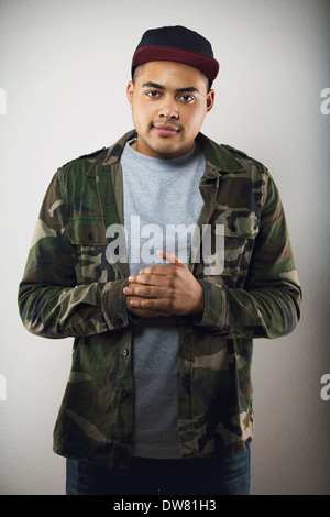 Gut aussehend männlichen Mode Model posiert in Freizeitkleidung auf grauem Hintergrund. Junger Mann, Blick in die Kamera tragen Camouflage Jacke. Stockfoto