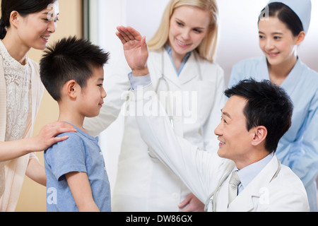 Arzt im Gespräch mit kleinen Jungen im Krankenhaus Stockfoto