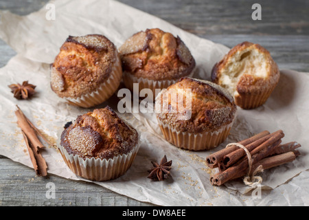 Hausgemachte Muffins mit braunem Zucker und Zimt serviert auf zerknittertes Papier über alten Holztisch Stockfoto