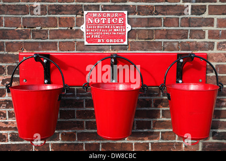 Rotes Feuer Eimer auf der Plattform Sheringham Station in North Norfolk. Stockfoto