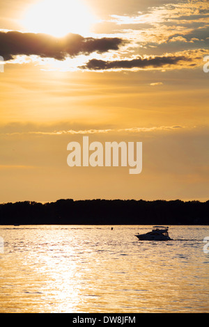 Bewölkten Sonnenuntergang mit Silhouette der einsame Boot Stockfoto