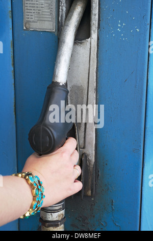 Zarte Frauenhand hält Kraftstoff-Pumpe-Düse mit Benzin oder Tankstelle. Stockfoto