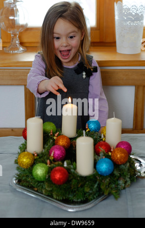 Mädchen genießen die erste brennende Kerze auf dem Adventskranz Stockfoto