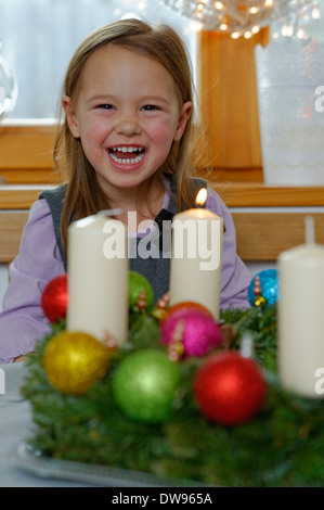 Mädchen genießen die erste brennende Kerze auf dem Adventskranz Stockfoto