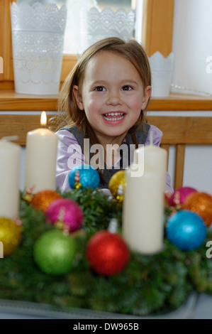 Mädchen genießen die erste brennende Kerze auf dem Adventskranz Stockfoto