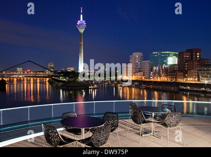 Restaurant-Terrasse mit Rheinturm Turm und die Gehry-Bauten zur blauen Stunde, Neuer Zollhof, Medienhafen, Düsseldorf Stockfoto